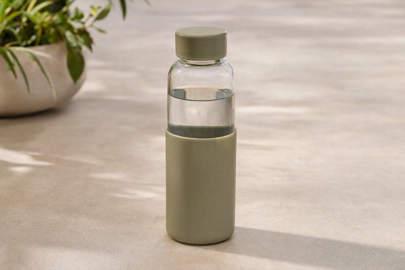 Studio 500 glass bottle with a muted sage sleeve on a desk